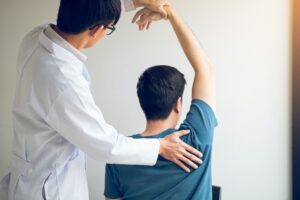 Chiropractor stretching a young man arm in medical office