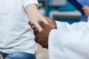 Closeup of african american pediatrician doctor rubbing injured arm of little patient